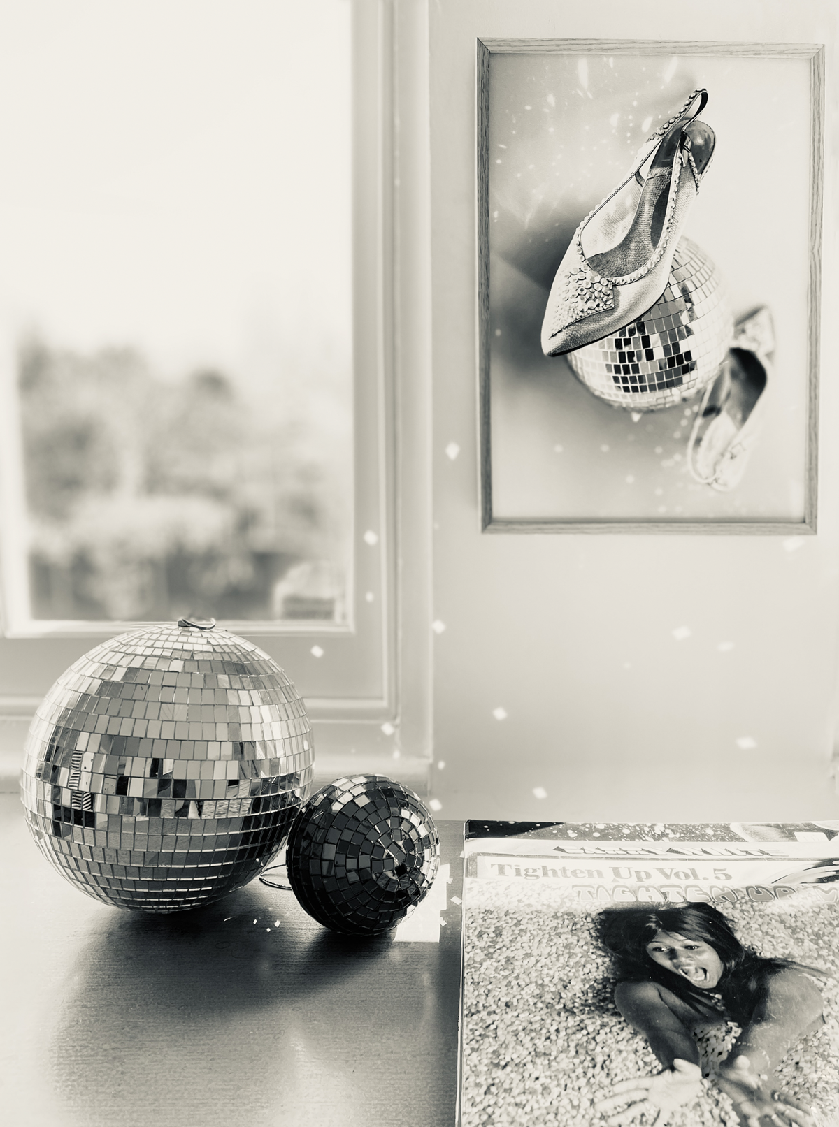 Decorative mirror balls and framed picture of high heels with disco ball on a wall.
