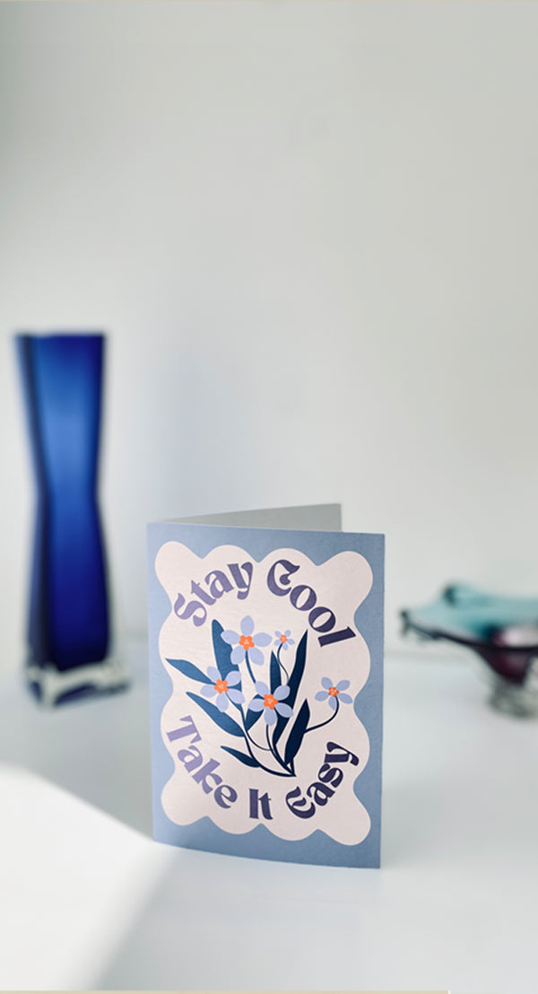 Card with 'Stay Cool, Take It Easy' text and floral design on a blurred background