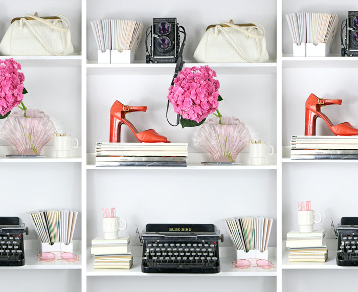 Shelves with decorative items including shoes, typewriters, and flowers on a white background