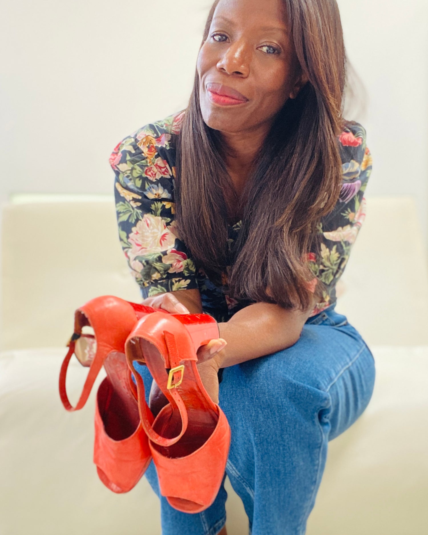 Colette holding orange shoes on a white couch