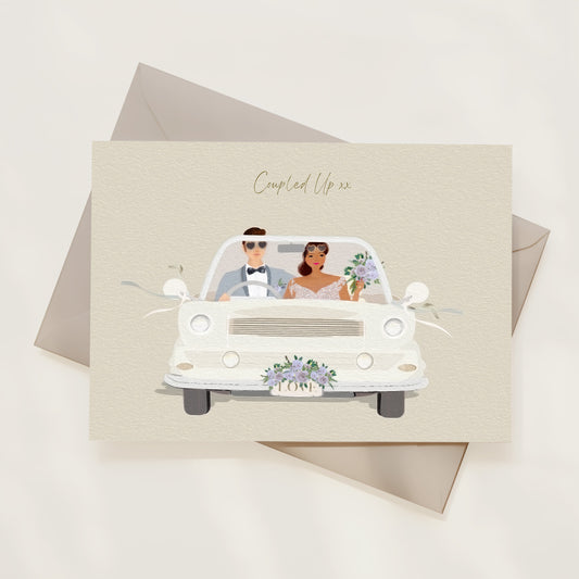Wedding card with illustration of a couple in a car alongside an envelope, on a light background