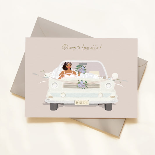 Card with a bride in a car illustration and 'Driving to Lovesville!' text on a beige background