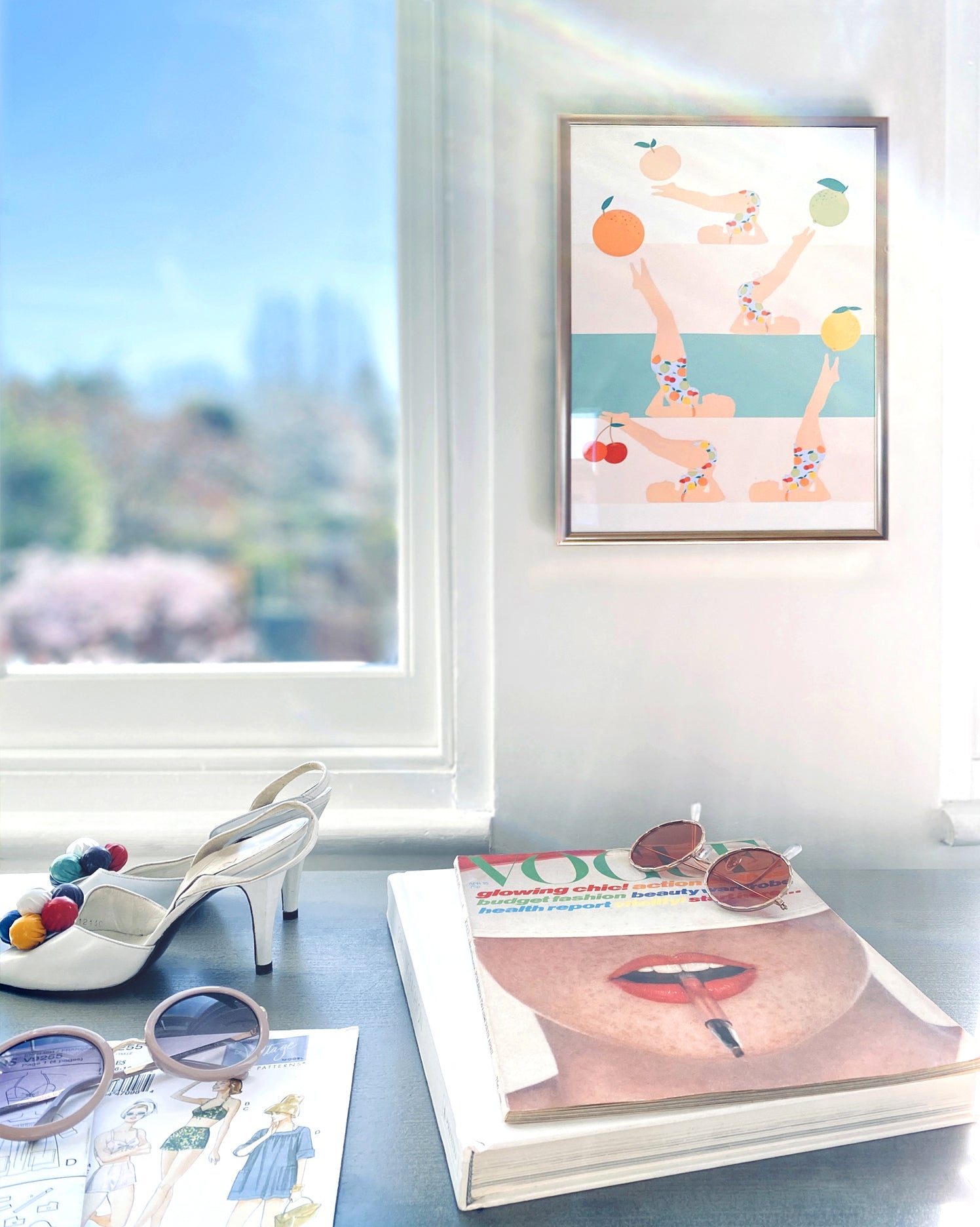 Framed artwork on a wall with books and shoes on a surface below.