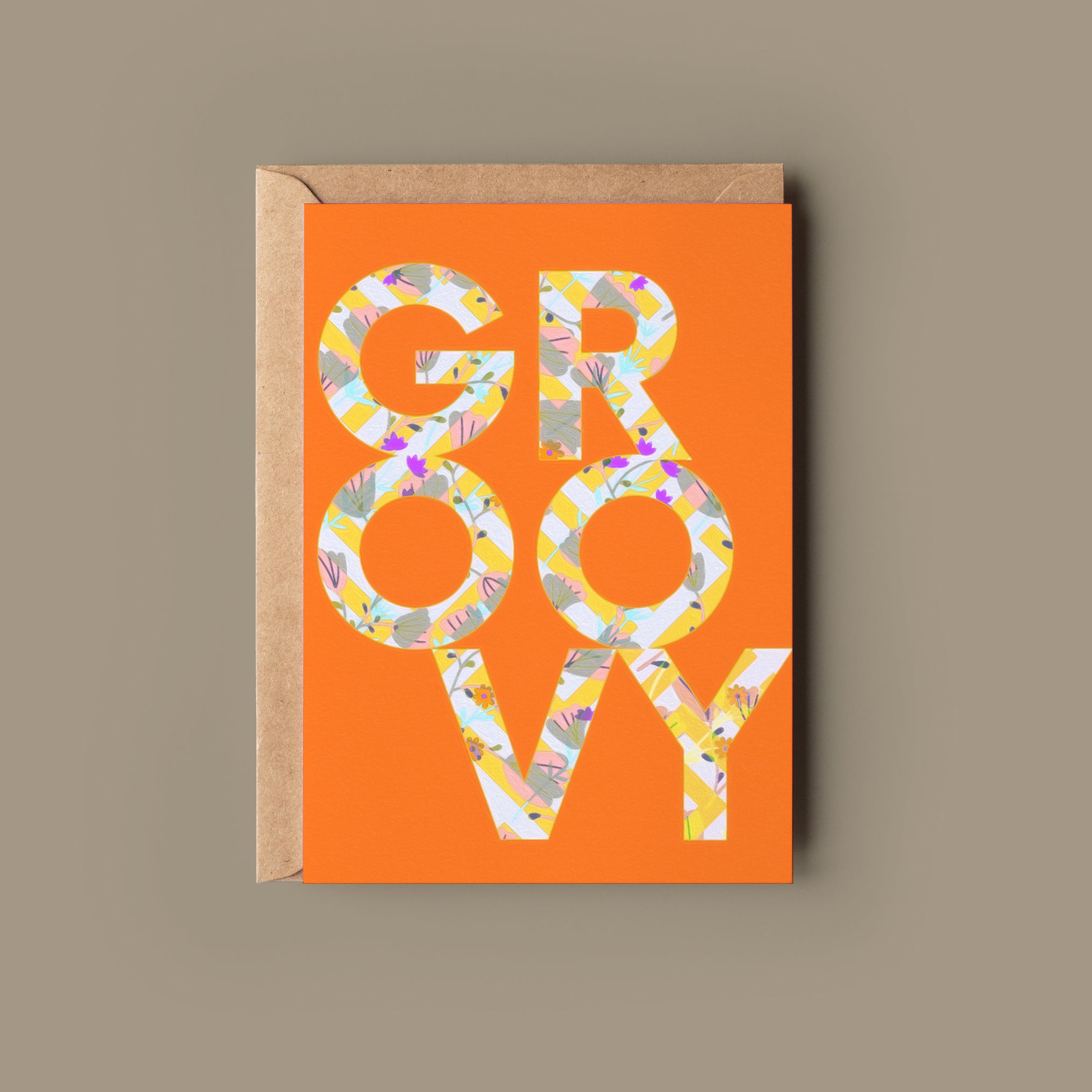 A colorful greeting card with 'GR-OO-VY' written in a stylized font on an orange background, accompanied by a kraft envelope.