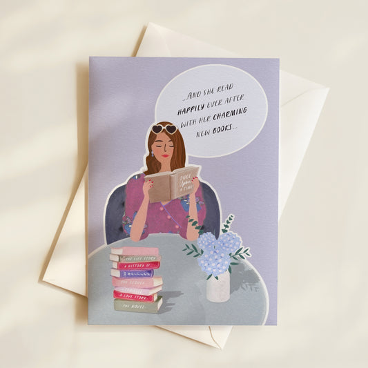 Greeting card with illustration of a woman reading a book, surrounded by books and flowers, on a light background.