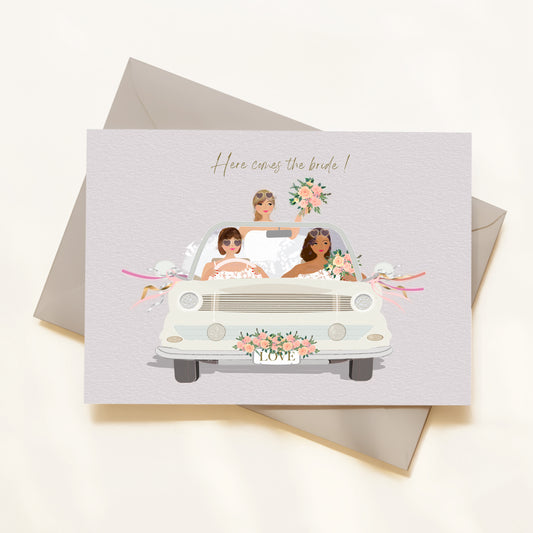 Wedding-themed card with illustration of a bride and bridesmaids in a car, accompanied by an envelope.