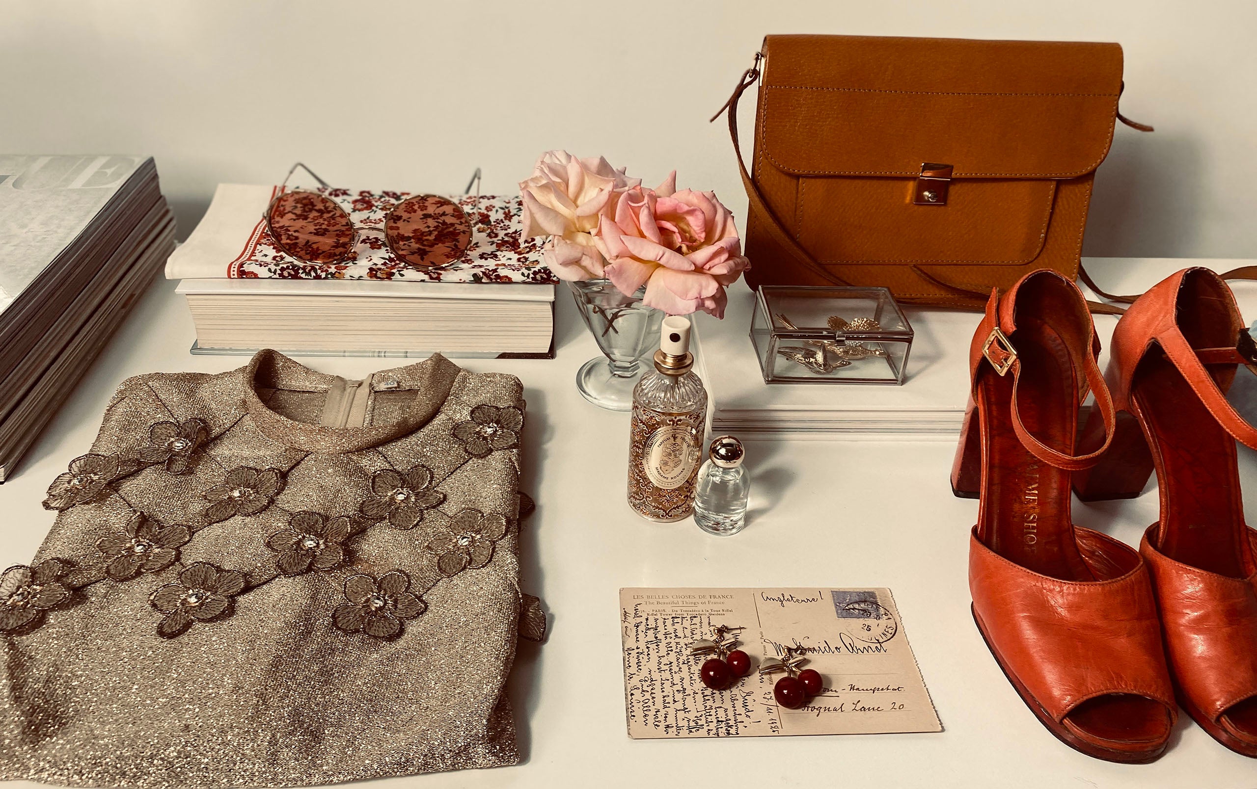 Collection of vintage fashion items including a sweater, shoes, handbag, and accessories on a table.
