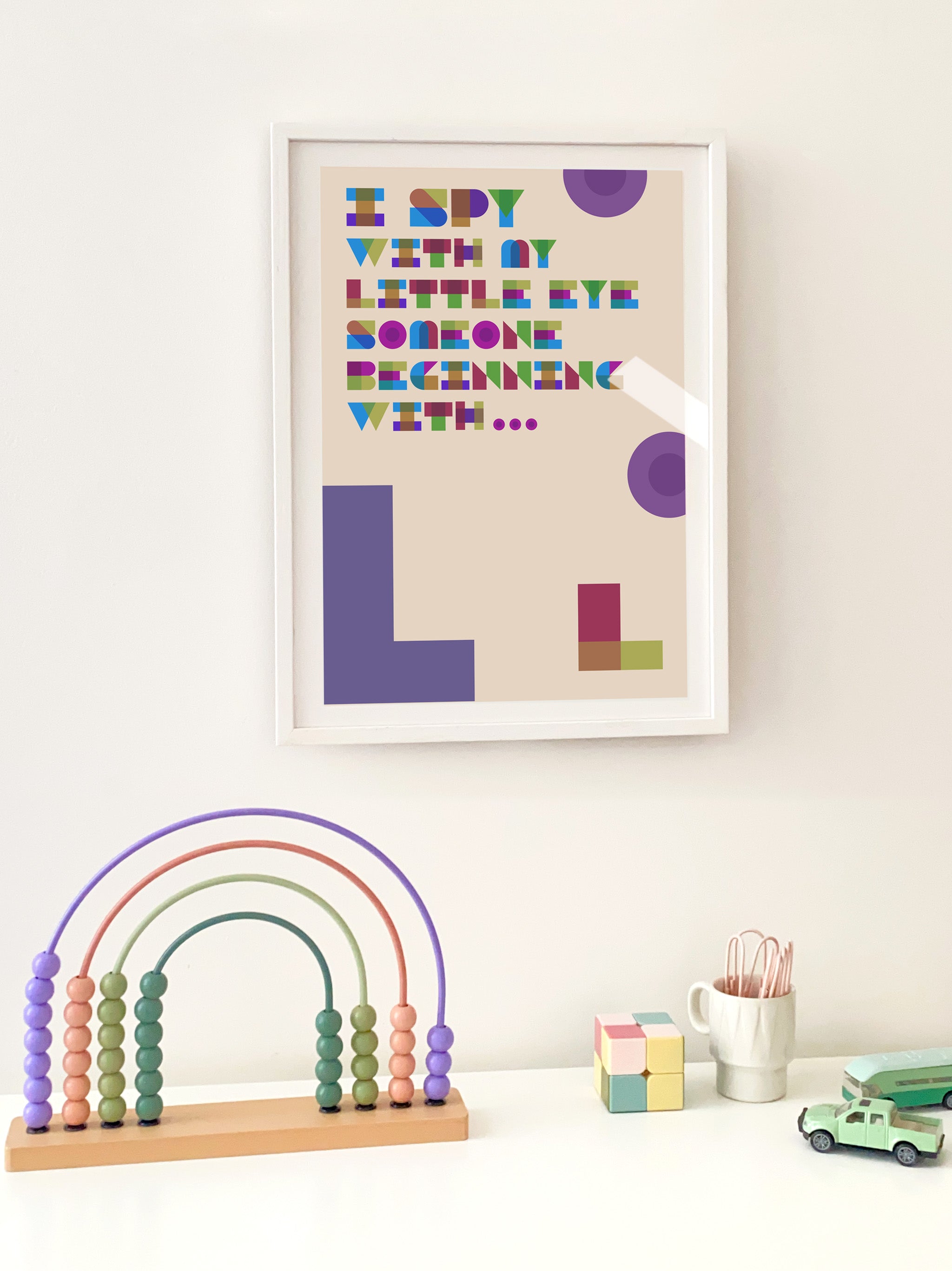 Framed children's art with colorful letters on a white wall, accompanied by educational toys.