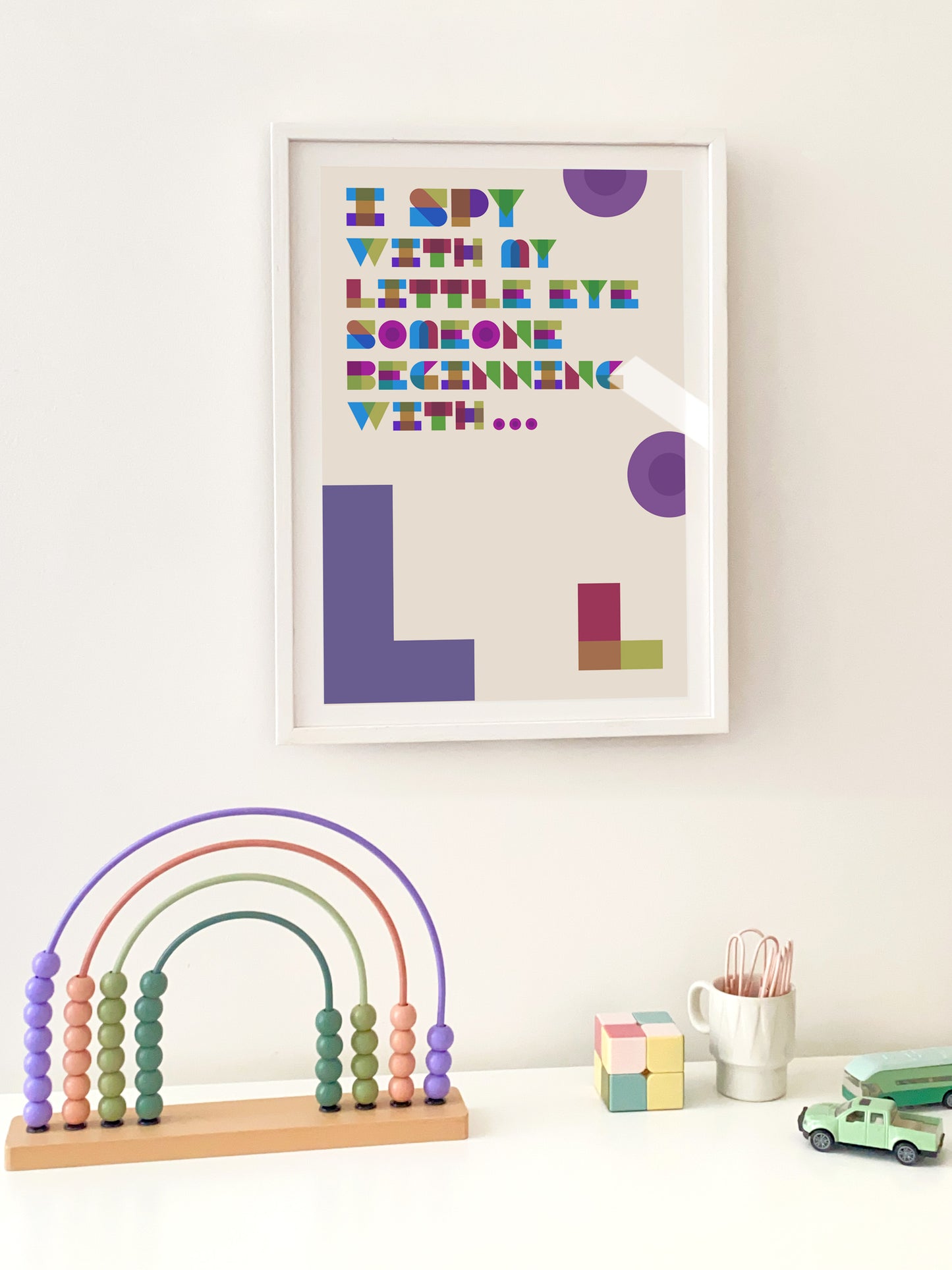 "L" Framed children's art with colourful letters on a white wall, accompanied by educational toys.