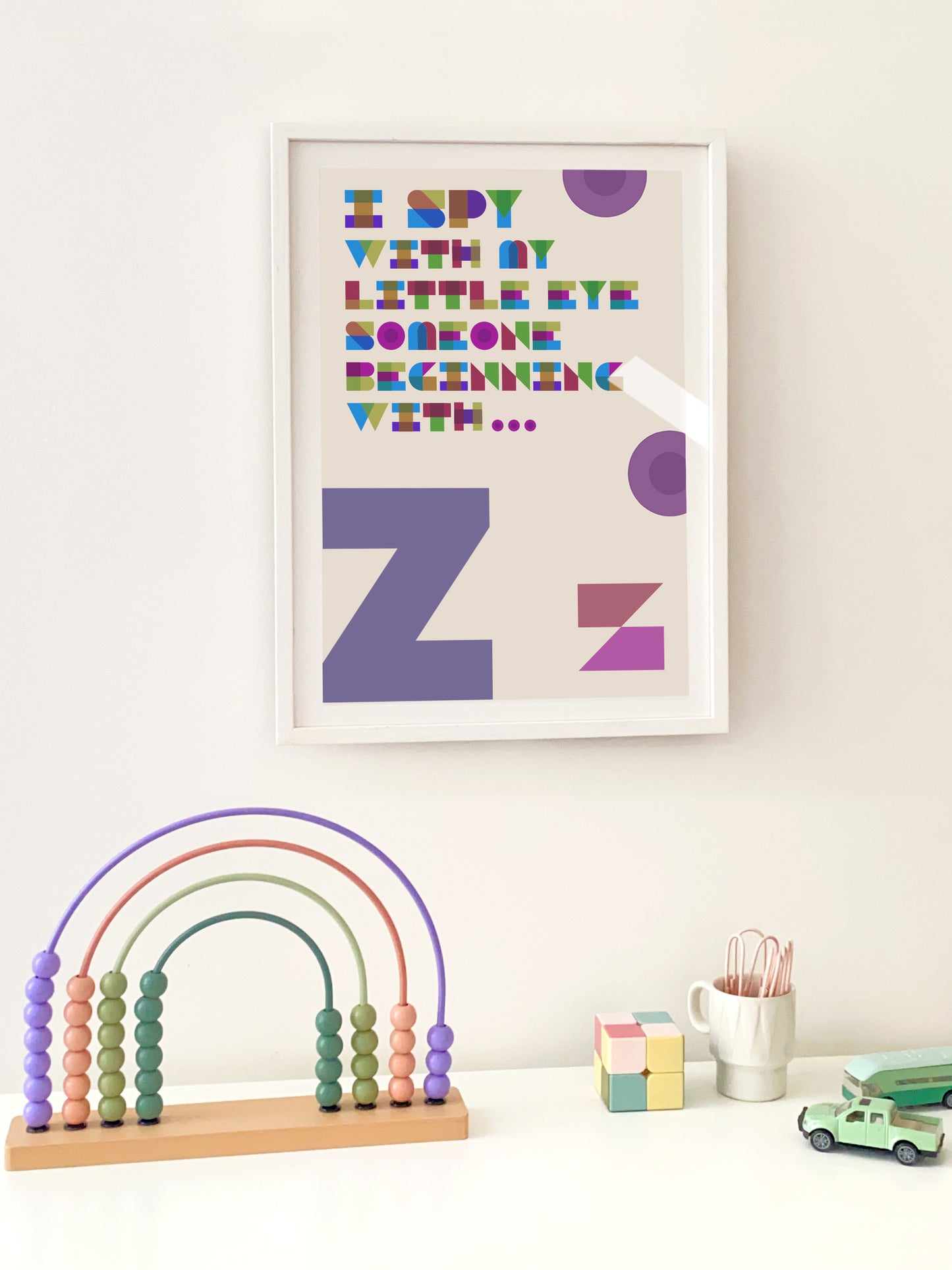 "Z" Framed children's poster with colourful text and letters, rainbow abacus, and toys on a white surface.