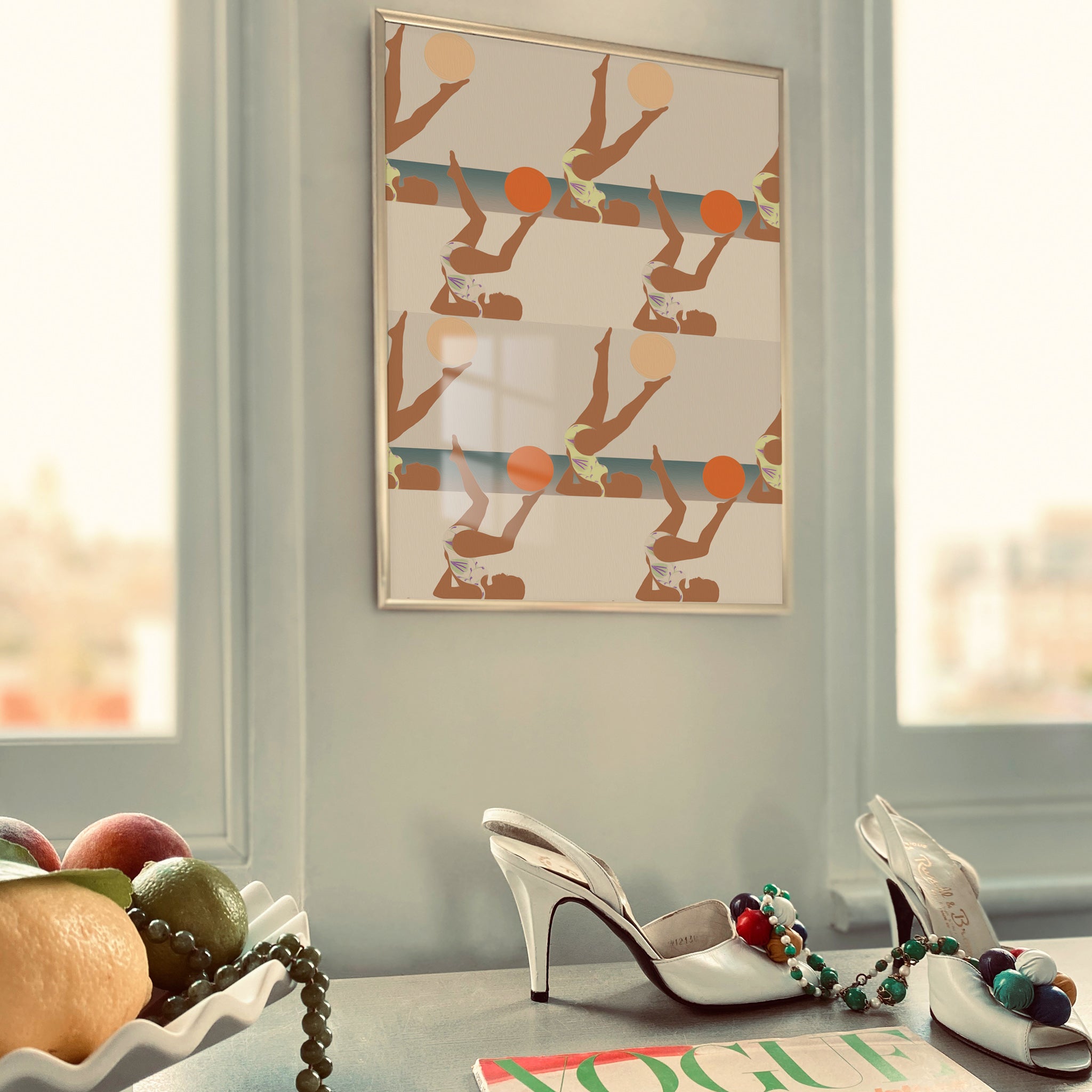 Pair of high-heeled shoes with decorative pom-poms on a surface, framed artwork on the wall.