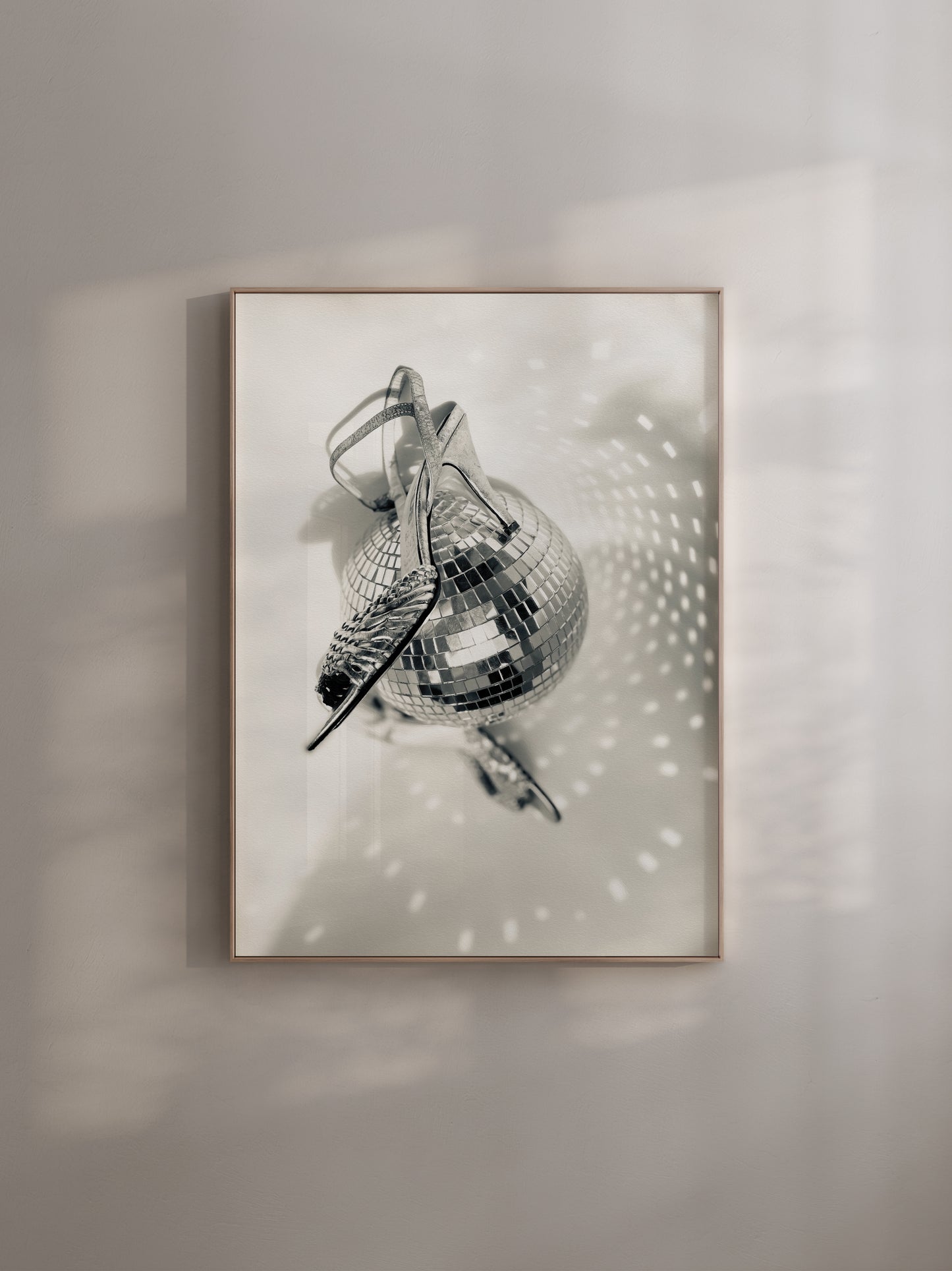 Framed artwork of a disco ball and shoes on a wall with soft shadows