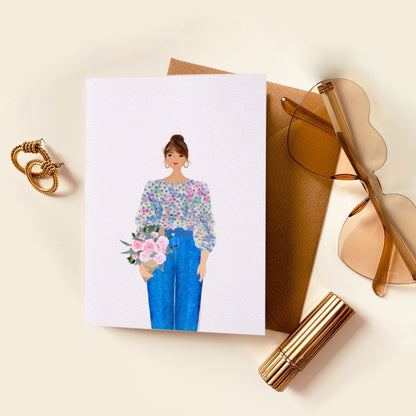 Card with illustration of a person holding flowers, sunglasses, and other items on a beige surface