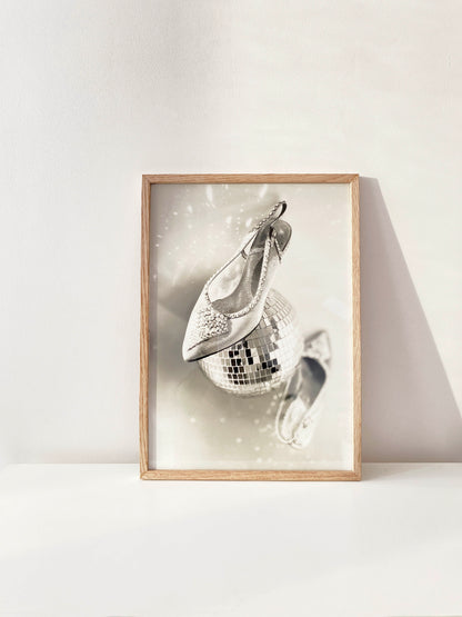 Framed artwork of high-heeled shoes and a disco ball on a white wall