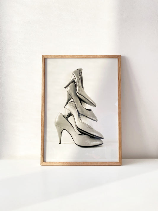 Framed artwork of four high-heeled shoes on a white background