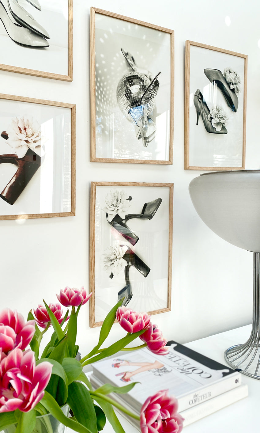 Decorative wall art with high heels and flowers on a white wall.